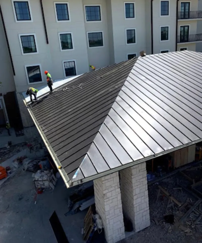 Crew installing standing seam metal roof panels on a commercial project in Fremont